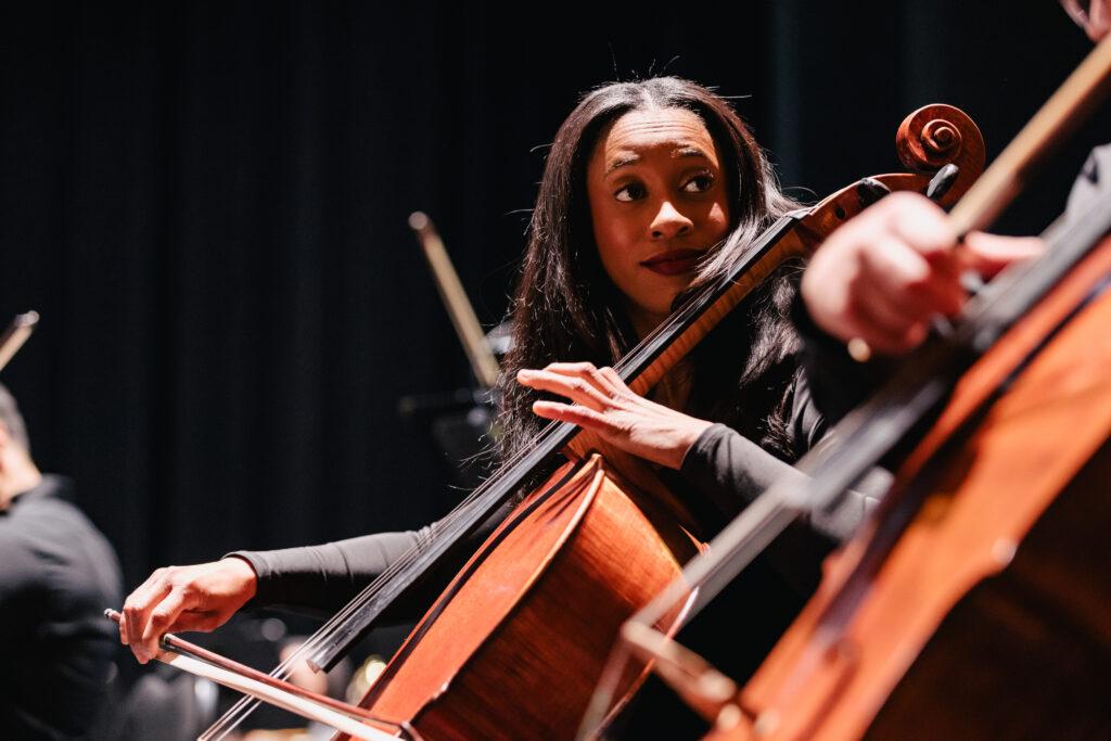 A black woman playing the chello.