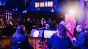 Musicians playing in a hall with purple lighting.